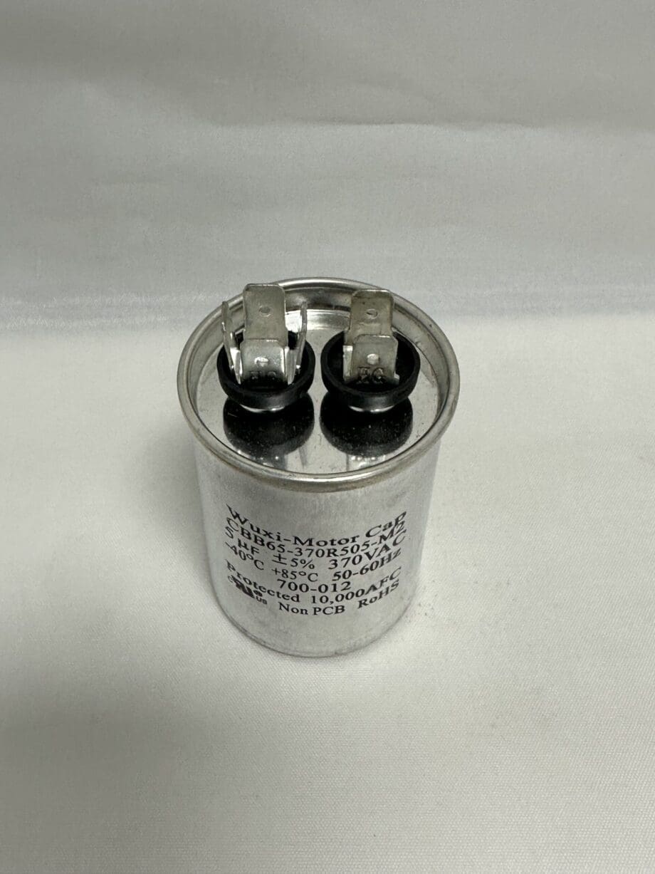 A CBB65-370R505-M2 5 uF 370 VAC cylindrical metal capacitor with two terminals on top and technical specifications labeled on its body, placed on a white surface and background.