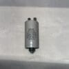 A cylindrical RPN0E106M8-M1 10 μF 250 VAC capacitor (part number 9310250100500) with two connectors on top, labeled 10μF ±5% 250VAC 250/85/21 20HS, resting on a white surface.